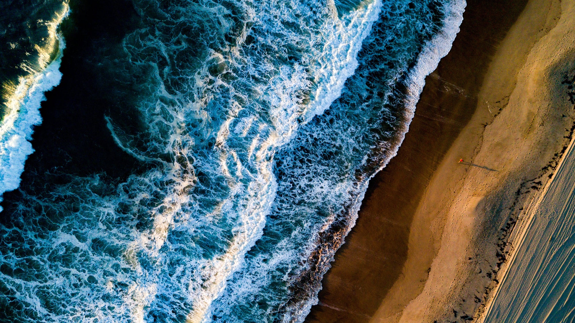 Top-down view of waves crashing onto a sandy beach